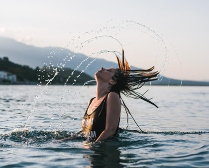 Frau schwimmt im Meer, wirft ihre nassen Haare in die Luft